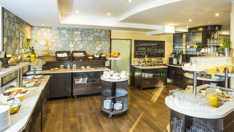 Ein Fr&uuml;hst&uuml;cksbuffet mit verschiedenen Speisen und Getr&auml;nken in einem hellen Raum.