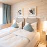 Gem&uuml;tliches Doppelzimmer mit zwei Einzelbetten, Holzw&auml;nden und moderner Dekoration.