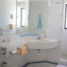 Helles Badezimmer mit Waschbecken, Spiegel, Dusche und Handt&uuml;chern.