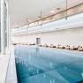 Innenansicht eines modernen Spa-Bereichs mit Pool und Liegest&uuml;hlen.
