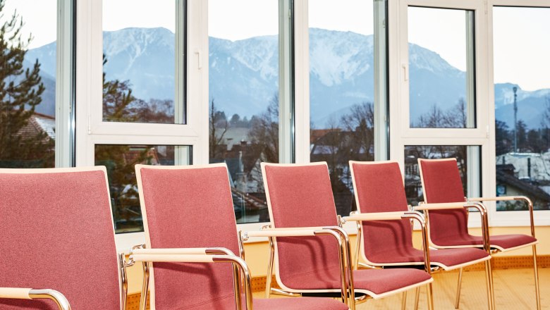 Seminarraum mit roten Stühlen und Bergblick durch große Fenster.
