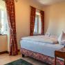 Gem&uuml;tliches Hotelzimmer mit Doppelbett, roten Vorh&auml;ngen und dekorativem Handtuch in Herzform.