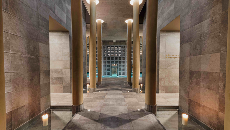 Innenansicht eines eleganten Spa-Bereichs mit S&auml;ulen und Kerzen.