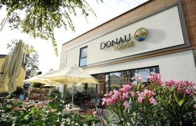 Außenansicht der Donau Lodge Ybbs mit Terrasse und Sonnenschirmen.