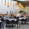 Innenansicht eines stilvollen Restaurants mit gedeckten Tischen und h&auml;ngenden Lampen.