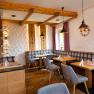 Gem&uuml;tliches Restaurant mit Holzm&ouml;beln, gedeckten Tischen und lila Vorh&auml;ngen.