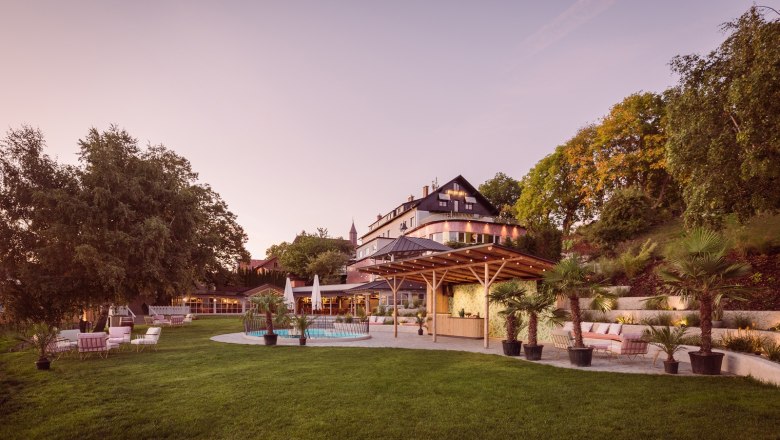 Großes Haus mit Garten und Pool bei Sonnenuntergang.