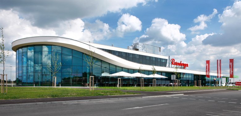 Modernes Gebäude mit Glasfassade und geschwungenem Dach.