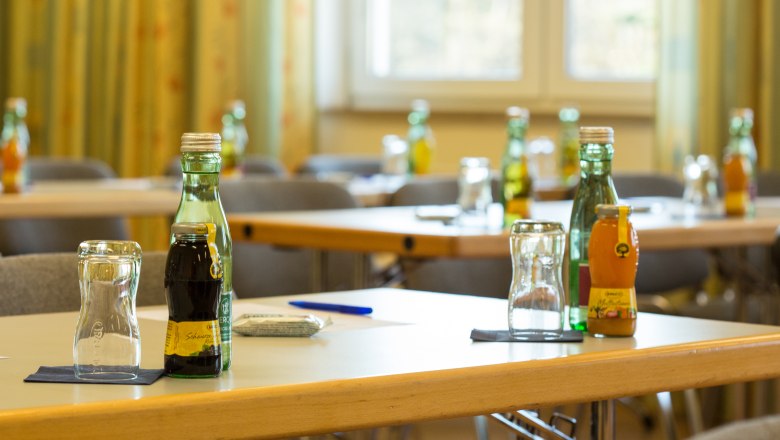 Ein Seminarraum mit Tischen, auf denen Getr&auml;nke und Gl&auml;ser stehen. Im Hintergrund sind St&uuml;hle und ein Fenster zu sehen.