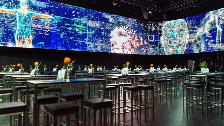 Ein moderner Showroom mit digitalen Projektionen und Tischen mit Blumen.