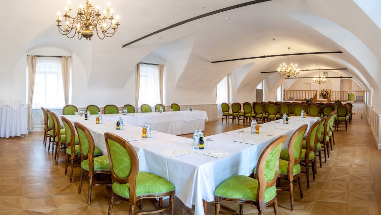 Eleganter Tagungsraum im Schloss Thalheim mit grünen Stühlen und Kronleuchtern.