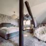 Luxuri&ouml;ses Schlafzimmer mit gro&szlig;em Bett, dekorativer Tapete, Kronleuchter und extravagantem Sessel mit Schwanendesign.