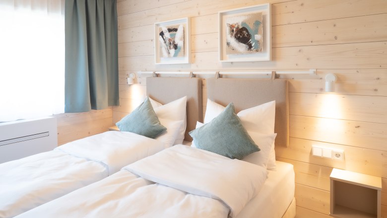 Doppelzimmer, © freilich / IsaBella Fritsche Gemütliches Doppelzimmer mit zwei Einzelbetten, Holzwänden und moderner Dekoration.