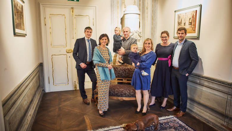 Eine Gruppe von Menschen posiert in einem eleganten Raum mit einem Hund im Vordergrund.