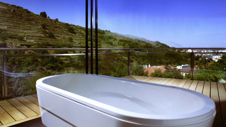 Panoramablick aus einem Badezimmer mit Badewanne und Blick auf Weinberge.
