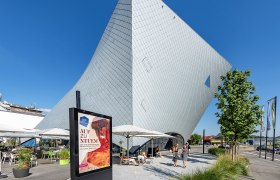 Moderne Architektur der Landesgalerie Niederösterreich in Krems mit Besuchern und Werbeplakat im Vordergrund.