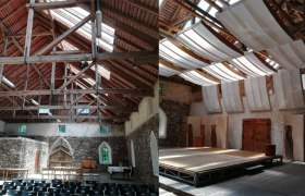 Innenansicht eines historischen Geb&auml;udes mit Holzdach und B&uuml;hne.