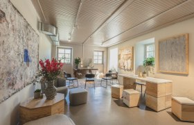 Ein stilvoll eingerichteter Raum mit modernen M&ouml;beln, Pflanzen und Kunstwerken an den W&auml;nden.