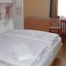 Hotelzimmer mit Doppelbett, zwei St&uuml;hlen und einem Tisch vor einem Fenster.