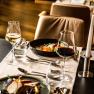 Eleganter Restauranttisch mit Weingl&auml;sern, Kerze und Gourmetgerichten.