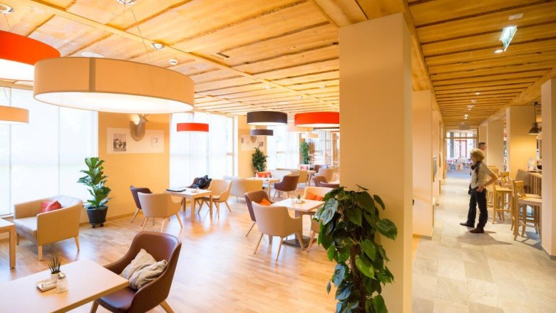 Lobby des JUFA Hotels Annaberg mit modernen M&ouml;beln und gro&szlig;en Lampen.