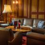 Gemütlicher Barbereich mit Ledersofas, Holztisch und Lampen.