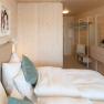 Modernes Doppelzimmer mit Holzw&auml;nden, Bett, Kissen und minimalistischer Einrichtung.