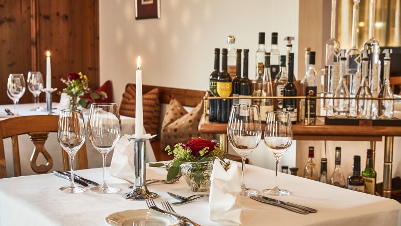 Eleganter Tisch in Hotel-Restaurant mit Weingl&auml;sern, Kerze und Blumen.
