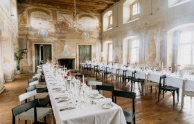Eleganter Speisesaal in einem Schloss mit langen, gedeckten Tischen und Wandmalereien.