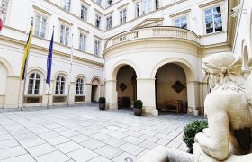 Innenhof des Palais Niederösterreich mit Flaggen und Statue.