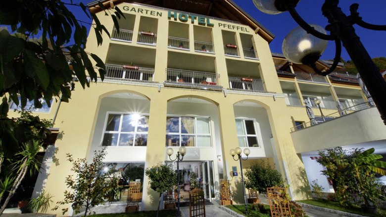 Au&szlig;enansicht des Gartenhotel Pfeffel mit gelber Fassade und Balkonen.