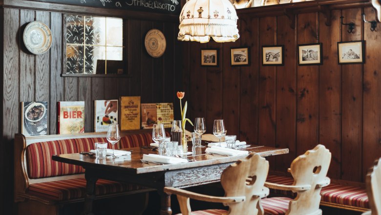 Gem&uuml;tliches Restaurant mit Holzw&auml;nden, rot gestreiften Sitzb&auml;nken und gedecktem Tisch.