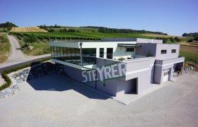 Modernes Weingut Steyrer mit Glasfassade und umliegenden Weinbergen.