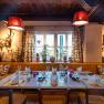 Gem&uuml;tlich dekoriertes Restaurant mit gedecktem Tisch, rustikalen Elementen und Pflanzen am Fenster.