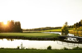 Golfplatz mit Teich und Brücke bei Sonnenuntergang im Golfresort Haugschlag.