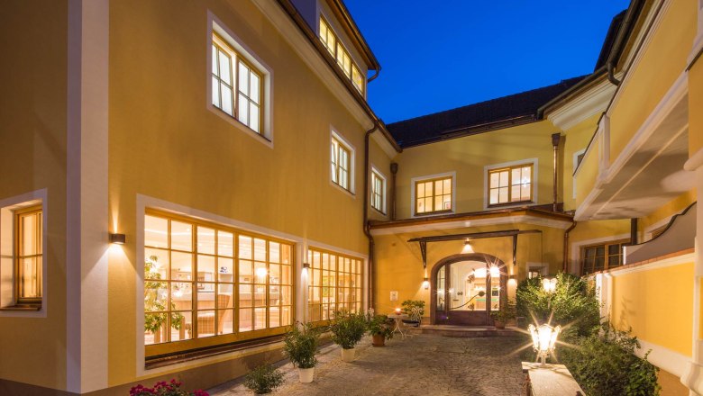 Innenhof des Hotel Zum Schwarzen B&auml;ren mit beleuchteten Fenstern und Pflanzen bei Nacht.