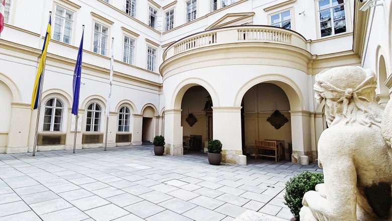 Innenhof des Palais Niederösterreich mit Flaggen und Statue.