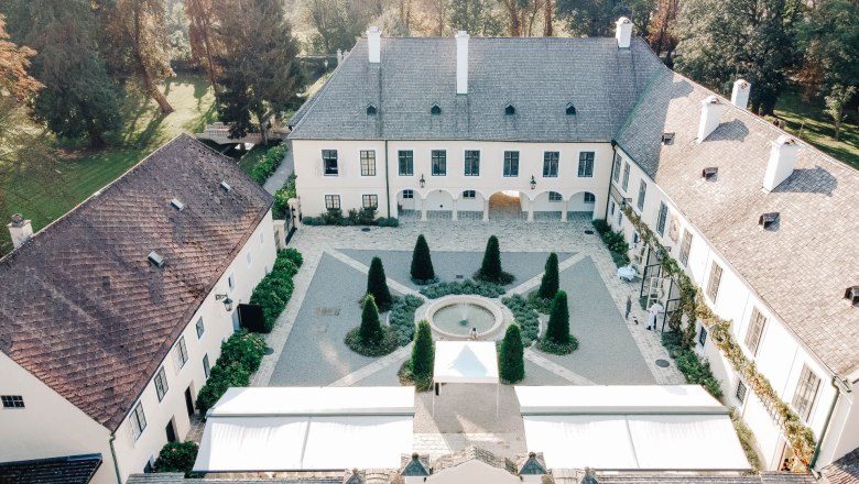 Luftaufnahme eines historischen Schlosses mit Innenhof und Garten.