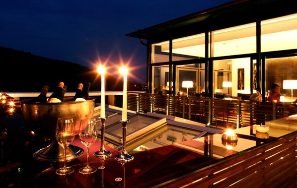 Abendliche Restaurantterrasse mit Kerzenlicht und Weingl&auml;sern.