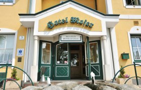 Eingang des Hotel Moser mit gelber Fassade und gr&uuml;nen T&uuml;ren.