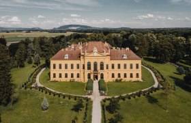 Luftaufnahme von Schloss Eckartsau umgeben von grüner Landschaft.