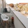 Balkon mit wei&szlig;em Stuhl und Blumenstrau&szlig;, Blick auf Stra&szlig;e und Geb&auml;ude.