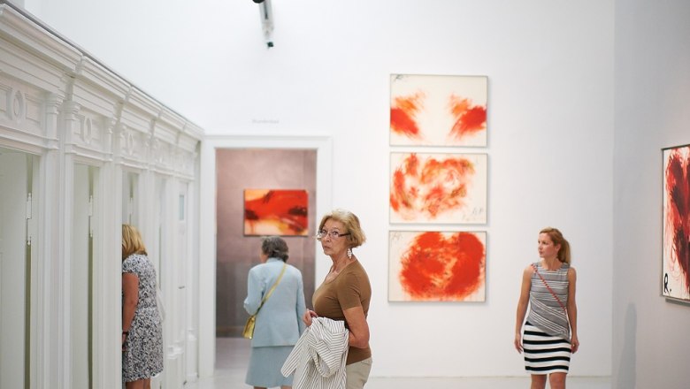 Besucher im Arnulf Rainer Museum betrachten Kunstwerke an wei&szlig;en W&auml;nden.