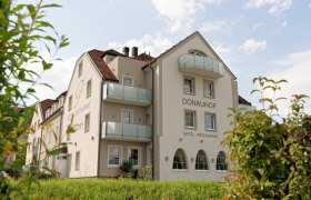Au&szlig;enansicht des Hotel Restaurant Donauhof mit Balkonen und Garten.