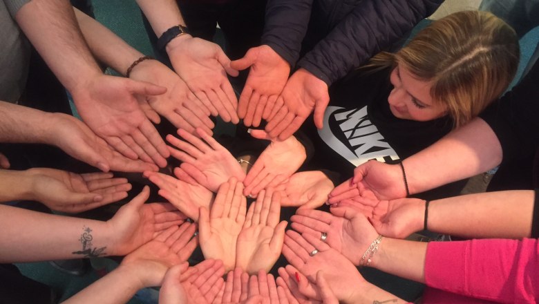 Mehrere Hände bilden einen Kreis, Handflächen nach oben.