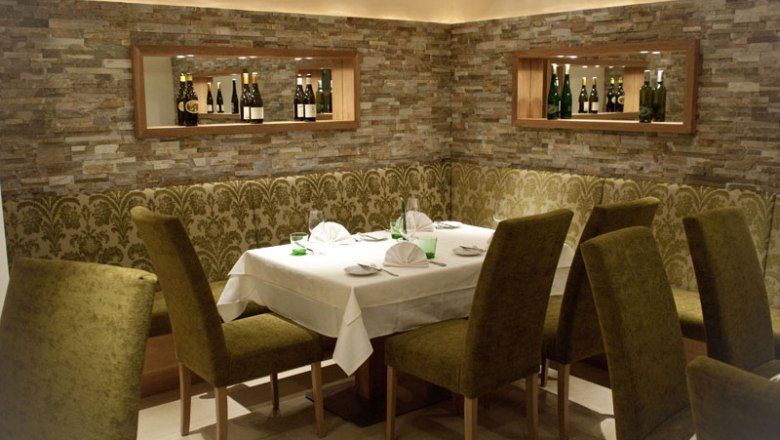 Elegantes Restaurant mit gedecktem Tisch und gr&uuml;nen St&uuml;hlen.