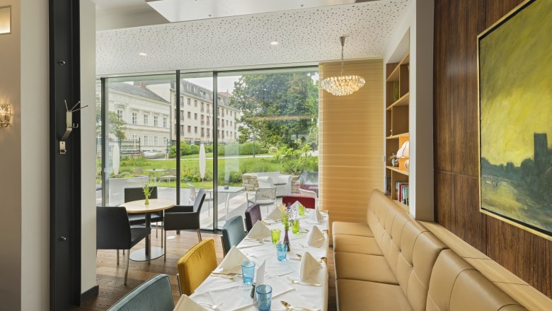 Elegantes Hotelrestaurant mit gedecktem Tisch und Blick auf den Garten.