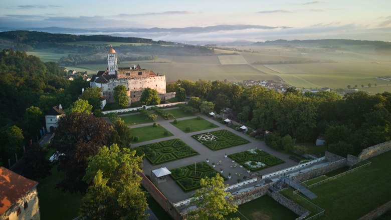 Luftaufnahme der Schallaburg mit Gartenanlage und umliegender Landschaft.