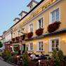 Fassade eines gelben Geb&auml;udes mit dem Schriftzug 'Hotel-Restaurant zur Post'. Vor dem Geb&auml;ude sitzen Menschen an Tischen.