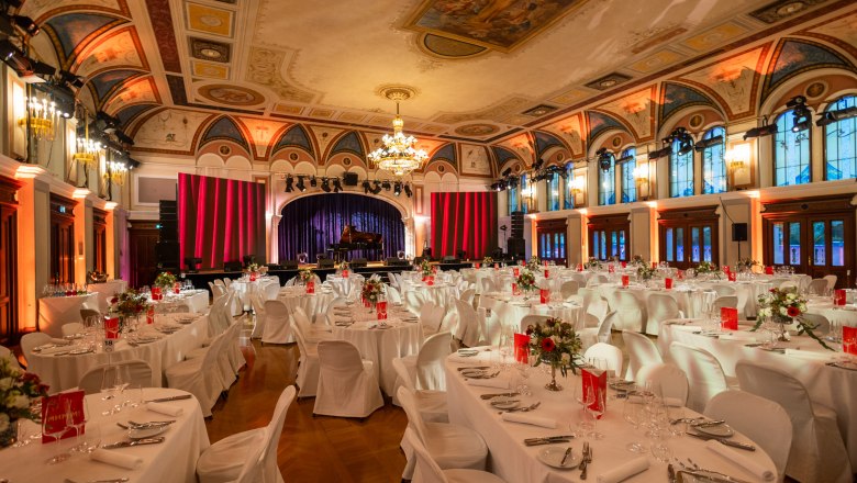 Eleganter Festsaal mit gedeckten Tischen und Bühne im Congress Center Baden.